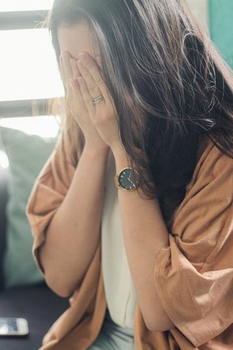 Woman covering her face with her hands.