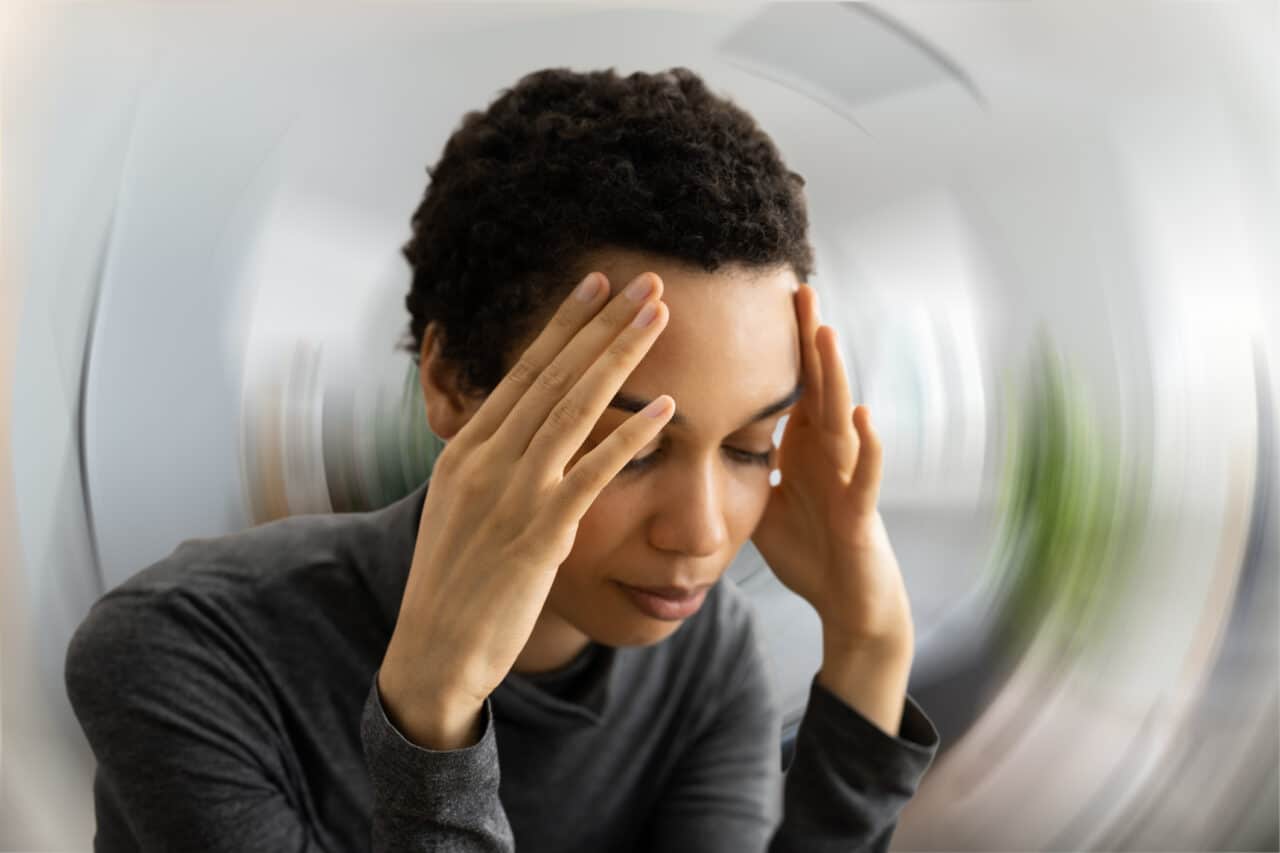 A woman experiencing a dizzy spell with a blurry, spinning background image