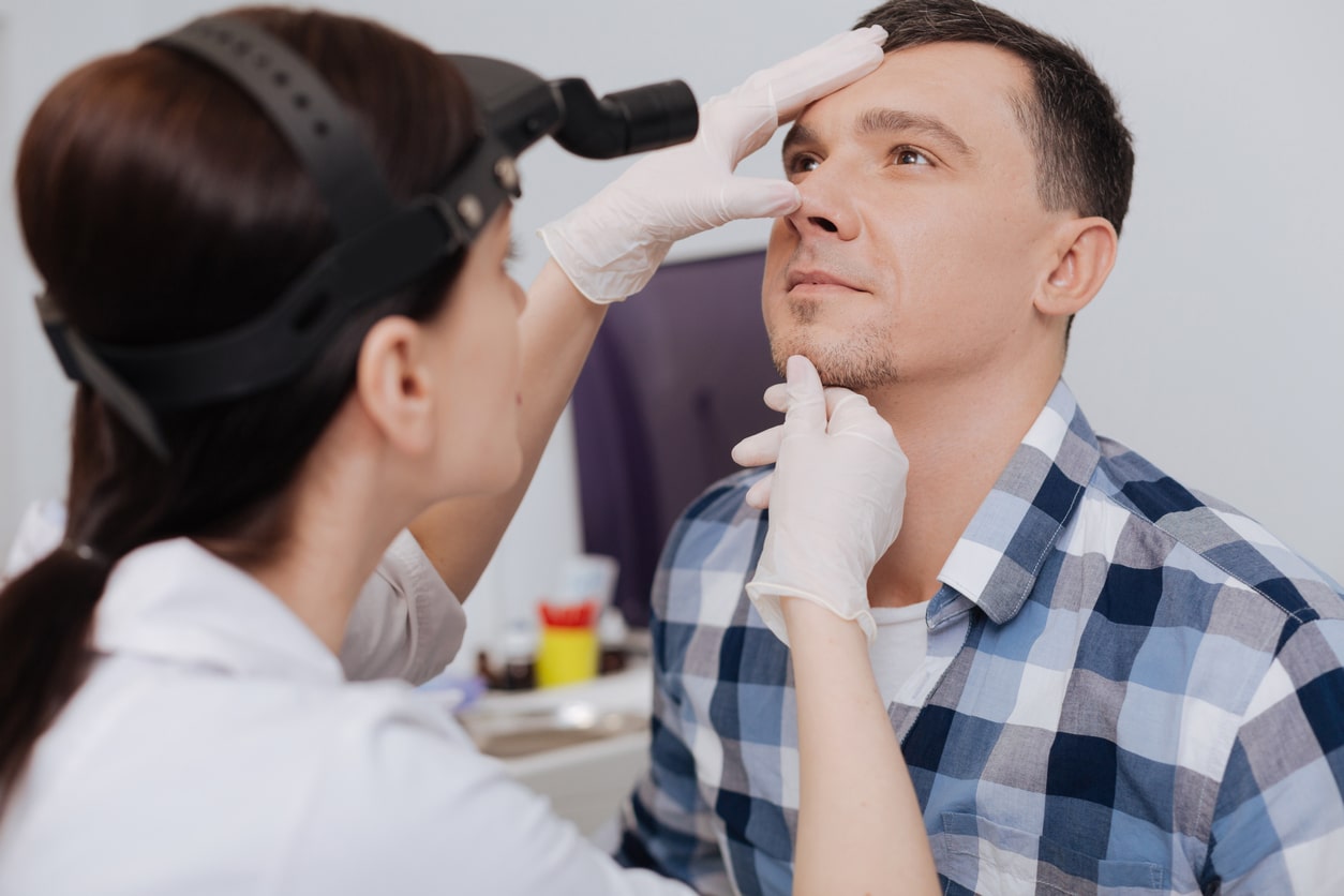 ENT specialist examining a man's nose.