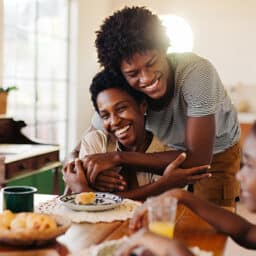 Happy son hugging his mom during a family breakfast.
